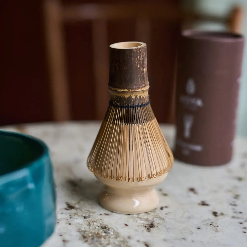 Bambusowa miotełka chasen na beżowej podstawce naoshi – tradycyjne akcesorium do przygotowywania matchy w stylu japońskim, na marmurowym blacie