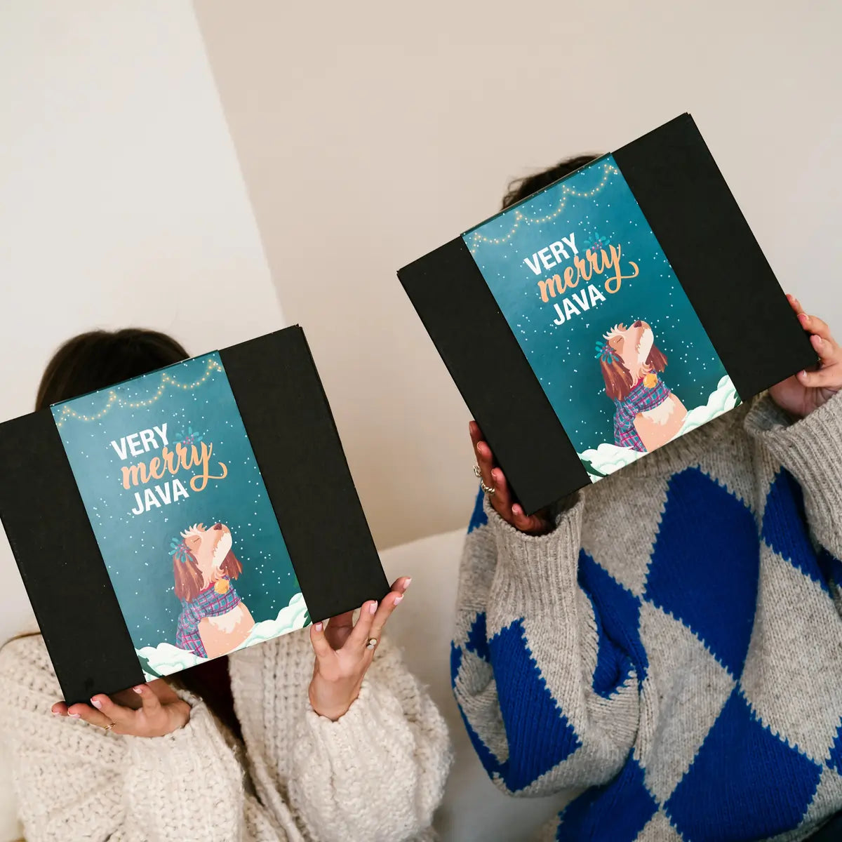 Zestaw świąteczny Very Merry Java w czarnym pudełku, trzymany przez dwie osoby – świąteczne opakowanie JAVA Coffee Roasters