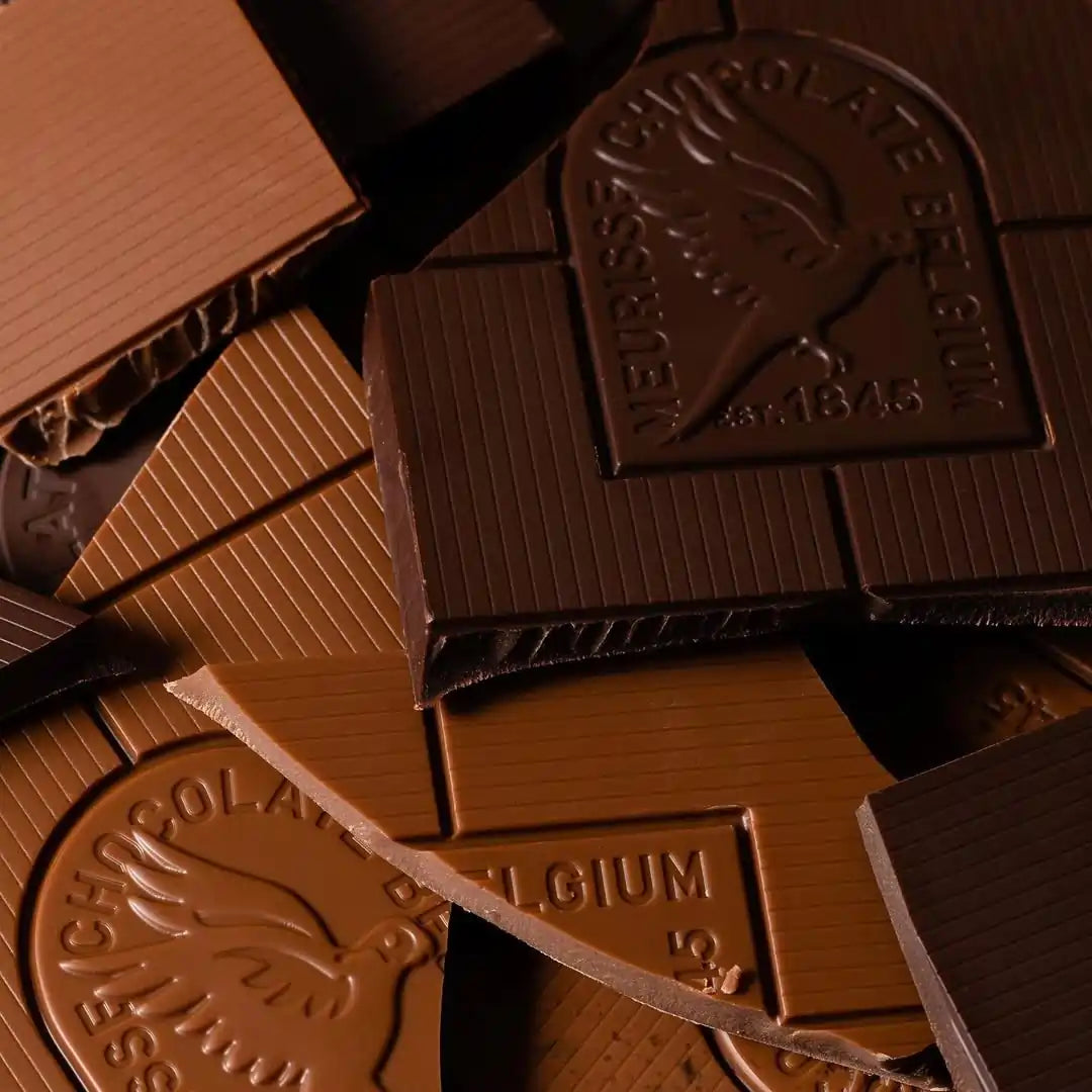 zbliżenie na kawałki ciemnej i mlecznej czekolady Meurisse z tłoczonym logo marki