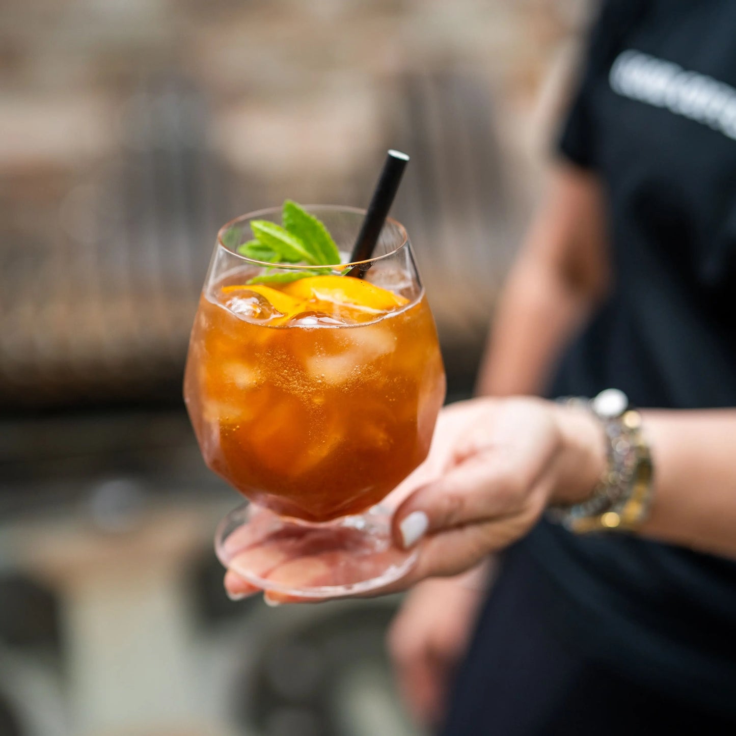 Szklanka z naparem z cascary, kostkami lodu, plasterkami pomarańczy i listkiem mięty