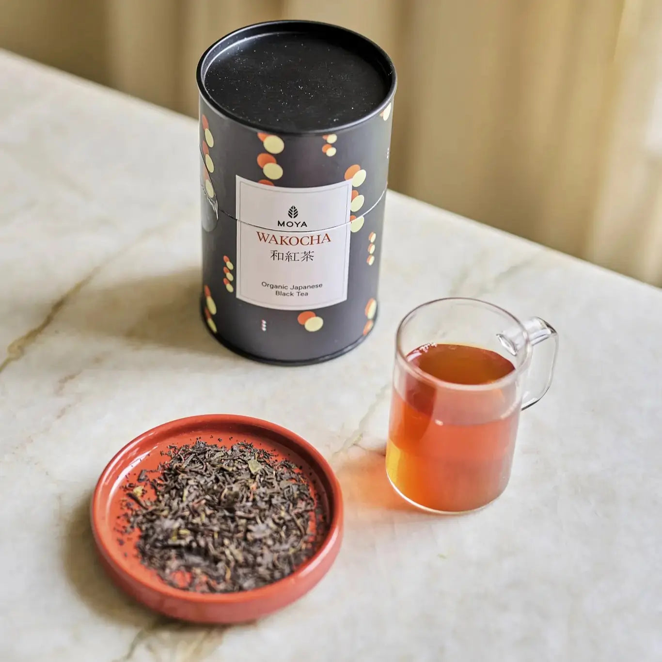 MOYA Wakocha – organiczna japońska czarna herbata liściasta w puszce, z suszem na spodku i gotowym naparem w szklance
