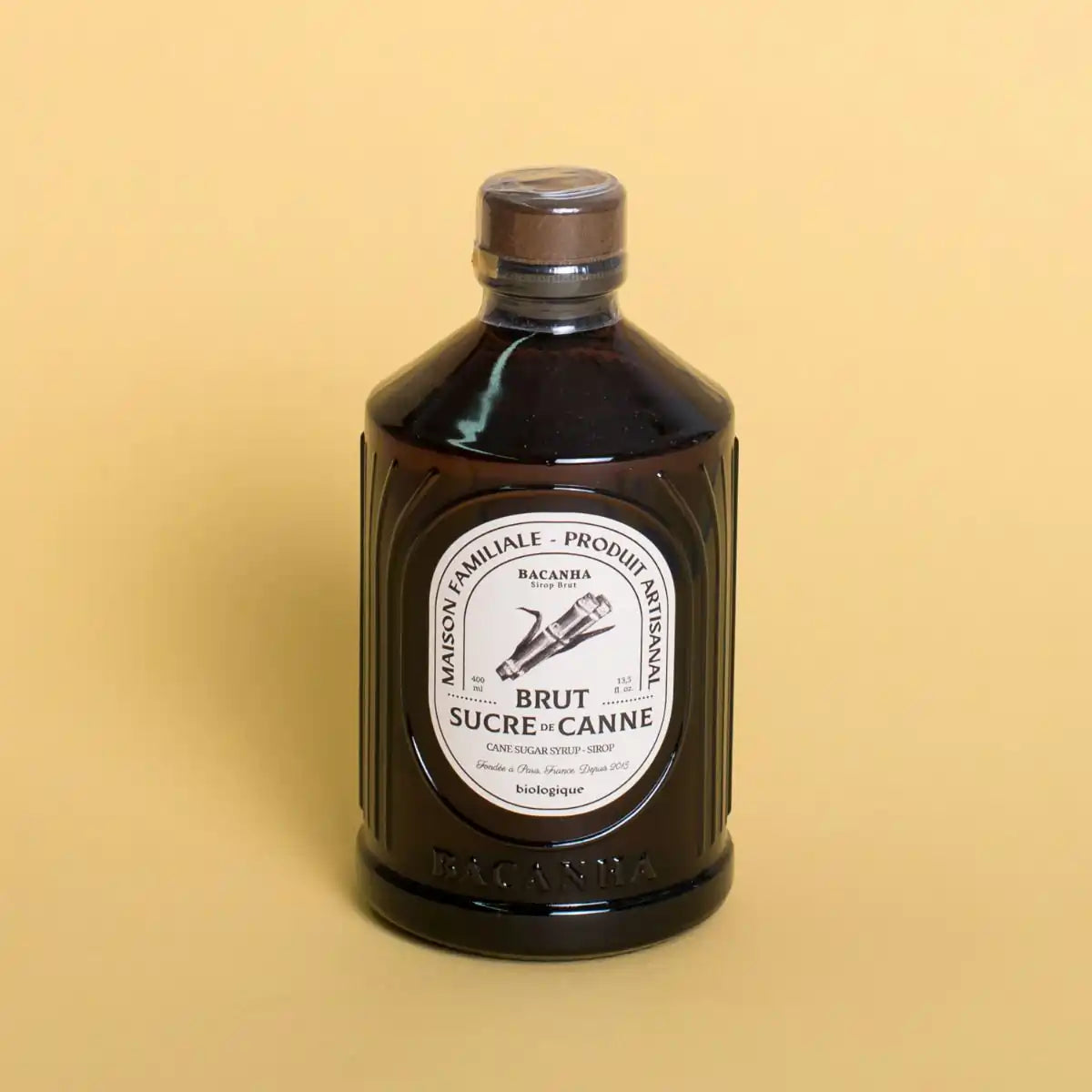 Butelka syropu Bacanha Sucre de Canne Brut 400 ml na żółtym tle – ekologiczny syrop z cukru trzcinowego