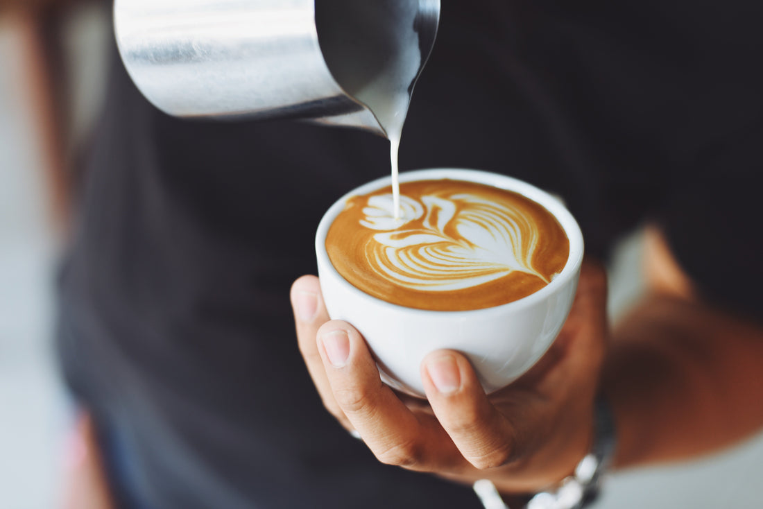 Filiżanka łagodnego cappuccino z mlekiem nalewanym przez baristę