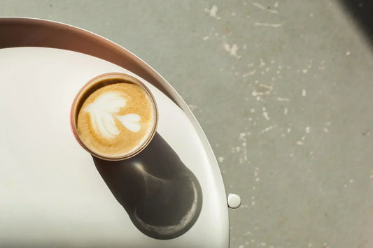 Filiżanka kawy flat white ustawiona na stoliku w słonecznym miejscu.