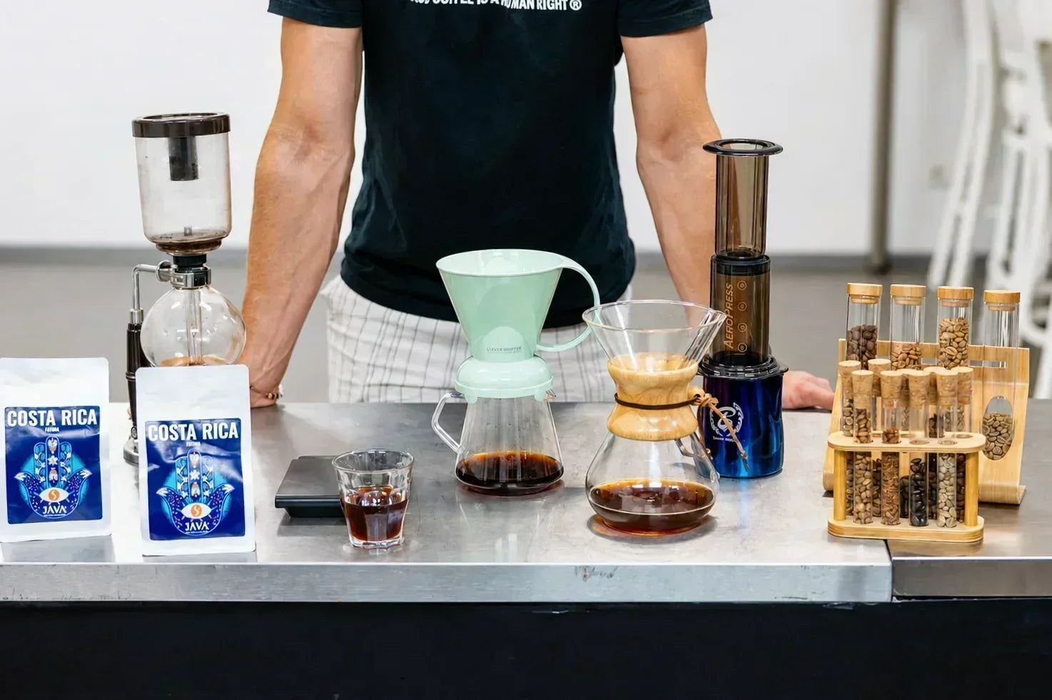 Zestaw metod parzenia kawy specialty na stole – V60, AeroPress i kawiarka obok opakowań kawy JAVA Coffee.