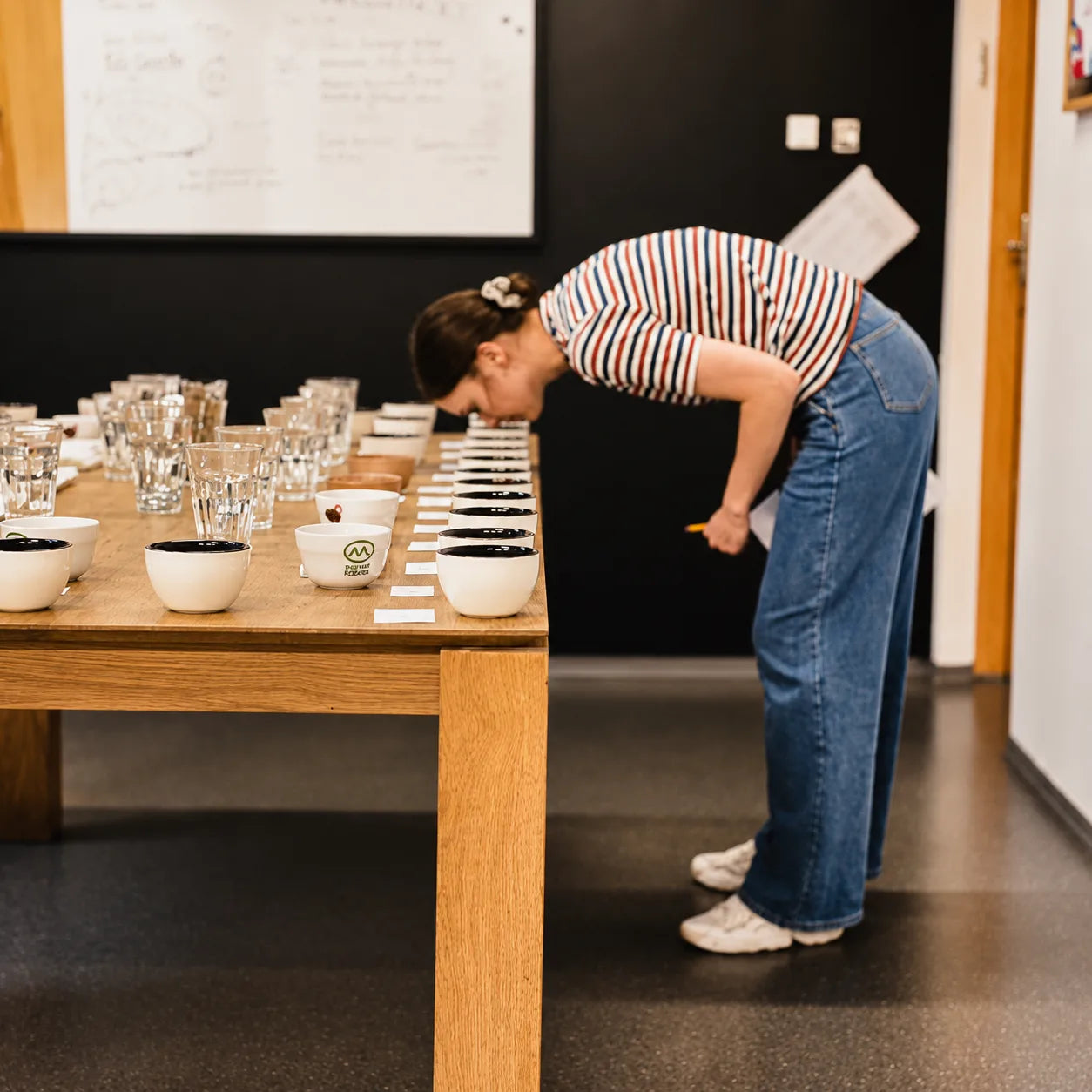 Uczestniczka szkolenia sensorycznego analizuje aromat kawy podczas cuppingu, porównując próbki specialty coffee w profesjonalnych miseczkach degustacyjnych.