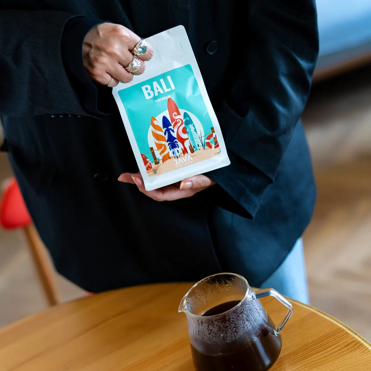 Kobieta prezentuje kawę specialty Bali Kintamani od JAVA Coffee z dzbankiem świeżo zaparzonej kawy przelewowej w Warszawie