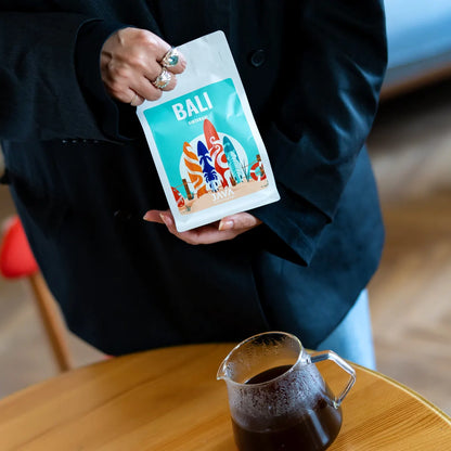 Kobieta prezentuje kawę specialty Bali Kintamani od JAVA Coffee z dzbankiem świeżo zaparzonej kawy przelewowej w Warszawie