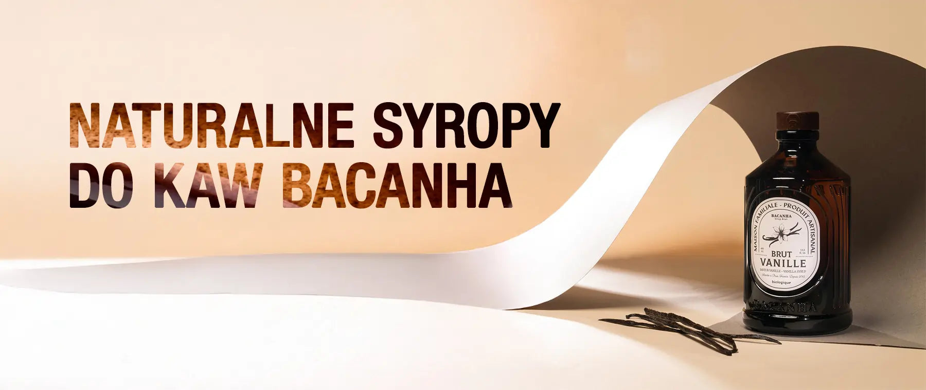 Baner promujący organiczne syropy do kaw Bacanha ze Francii. Po prawej stronie butelka syropu Brut Vanille w stylowej, bursztynowej butelce z elegancką etykietą. W tle jasne, minimalistyczne tło z delikatnie zwiniętym arkuszem papieru, obok leżą laski wanilii. Po lewej stronie dynamiczny napis: 'NATURALNE SYROPY DO KAW BACANHA