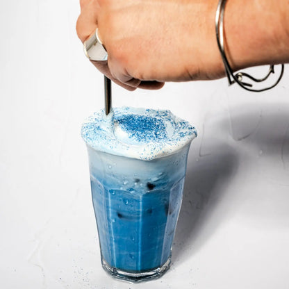 Mrożone niebieskie latte ze spiruliną i mleczną pianką przygotowywane w wysokiej szklance z lodem