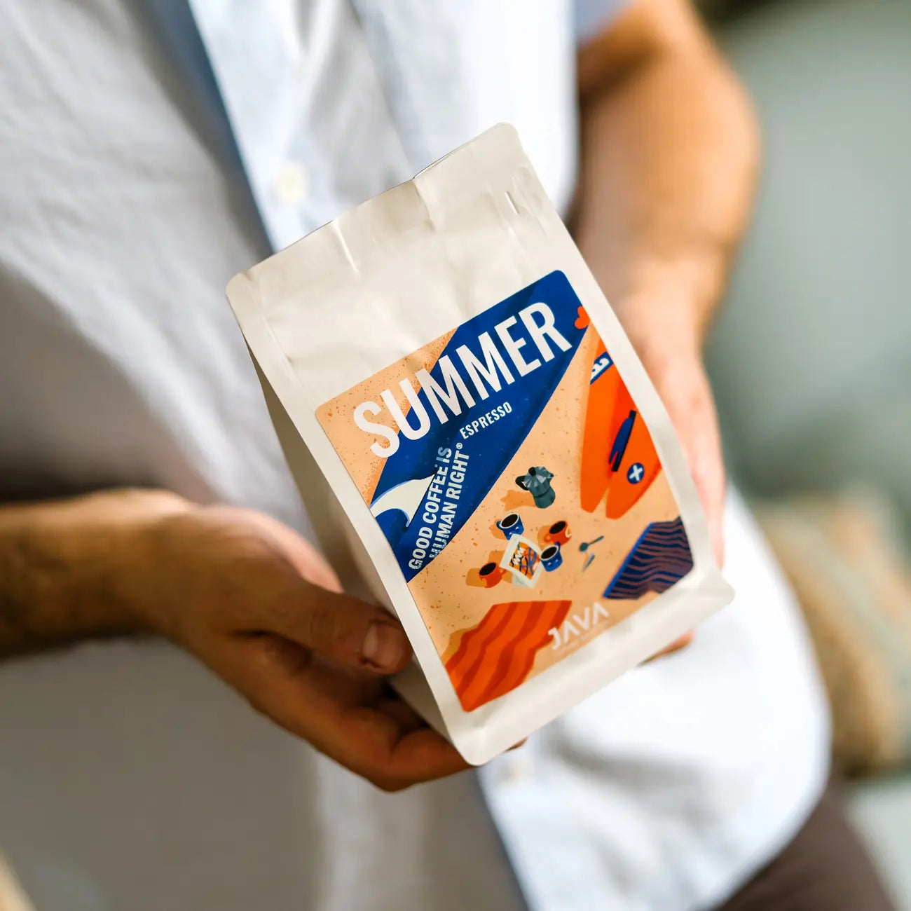 Burundi Ninga Summer Espresso JAVA Coffee Roasters trzymana w dłoni obok filiżanki świeżo zaparzonego espresso