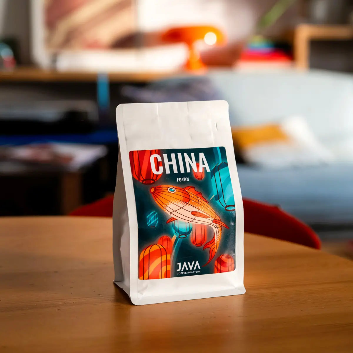 Opakowanie kawy specialty China Fuyan od JAVA Coffee Roasters ustawione na drewnianym stole we wnętrzu – zdjęcie lifestyle z wyraźną etykietą produktu