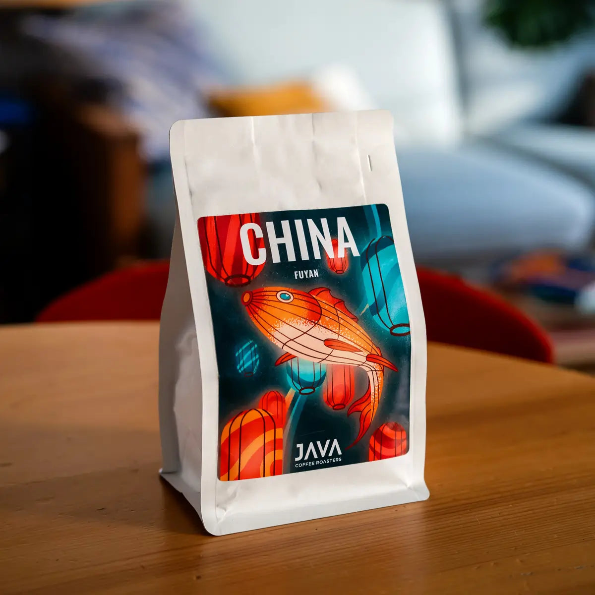 Opakowanie kawy specialty China Fuyan od JAVA Coffee Roasters ustawione na drewnianym stole, minimalistyczne zdjęcie produktowe z etykietą marki