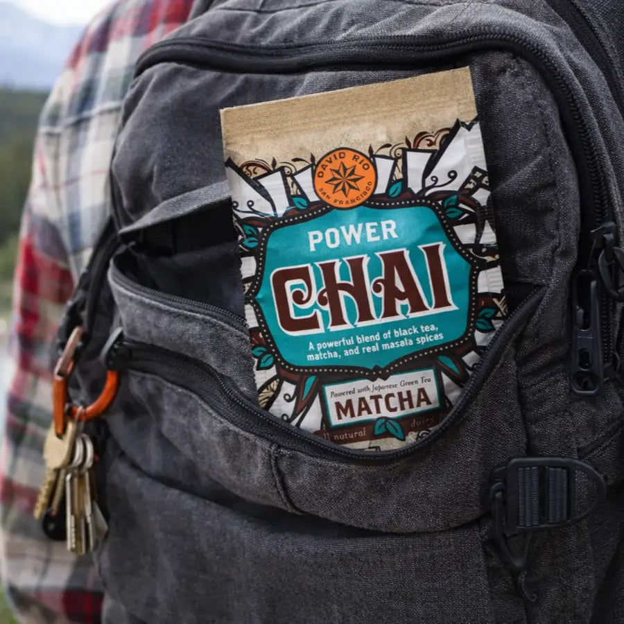 Power Chai Matcha David Rio – wegańska saszetka chai z matchą trzymana w dłoni podczas górskiej wędrówki, porcja na wynos