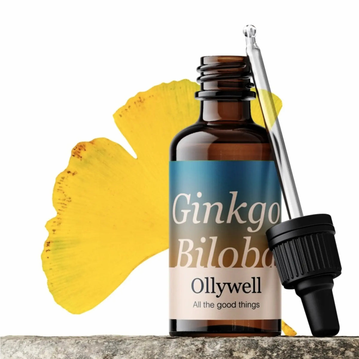 Otwarta butelka ekstraktu Ginkgo Biloba Ollywell ze szklaną pipetą i żółtymi liśćmi miłorzębu na białym tle.