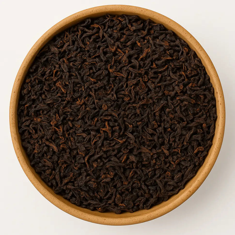 Sypane liście indyjskiej herbaty Assam Fairtrade widziane z góry na białym tle, wypełniające całą kompozycję