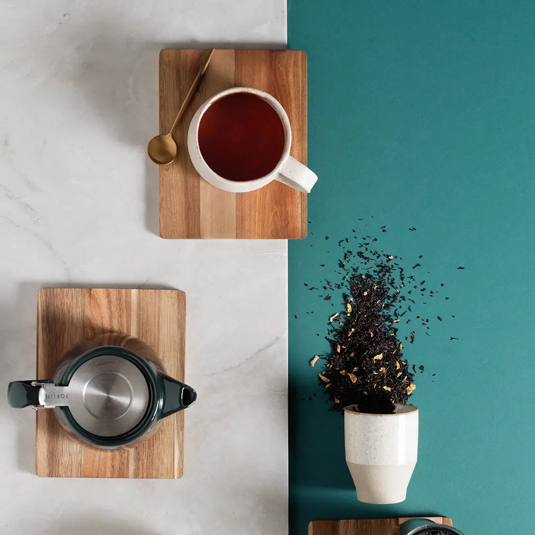 Herbata Indian Spiced Chai SUKI Tea – filiżanka zaparzonej czarnej herbaty z przyprawami korzennymi i imbirem, obok rozsypane liście herbaty, widok z góry