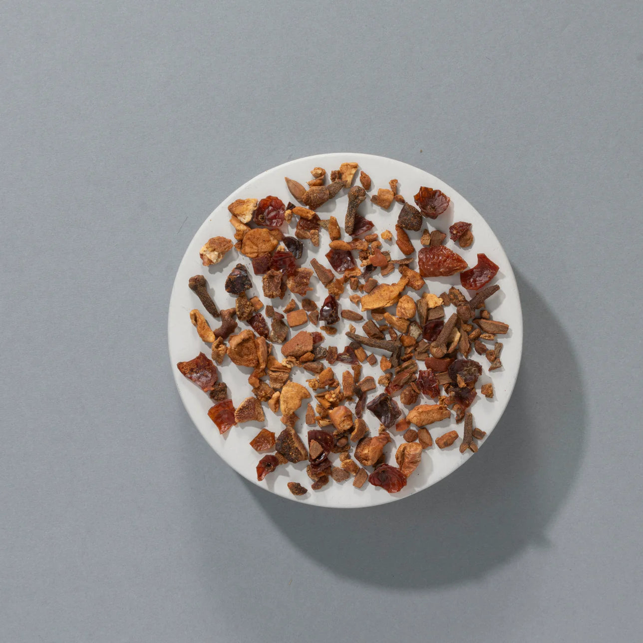 Herbata owocowa Partridge in a Pear Tea SUKI Tea – suszone składniki herbaty: jabłko, gruszka, hibiskus, cynamon i goździki, widok z góry na białym tle.