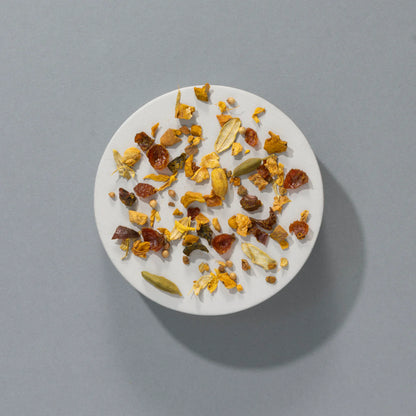 Sypana herbata Suki Spiced Pumpkin Pie widziana z góry – mieszanka suszonych owoców, przypraw i ziół na jasnym talerzyku, na szarym tle.
Sypana herbata Suki Spiced Pumpkin Pie widziana z góry – mieszanka suszonych owoców, przypraw i ziół na jasnym talerzyku, na szarym tle.