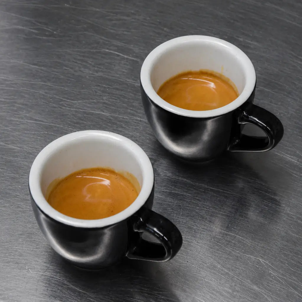 Dwie filiżanki świeżo zaparzonego espresso z gęstą cremą przygotowane z kawy JAVA Coffee Roasters w palarni kawy specialty w Warszawie.