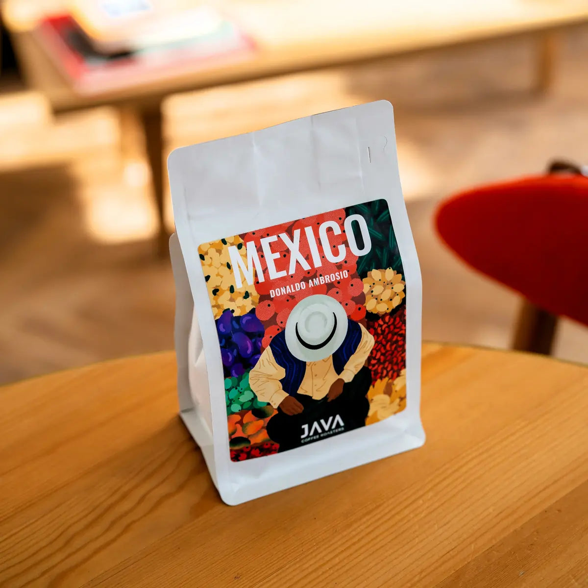 Opakowanie kawy specialty Mexico Donaldo Ambrosio od JAVA Coffee Roasters ustawione na drewnianym stole, zdjęcie lifestyle w jasnym wnętrzu.