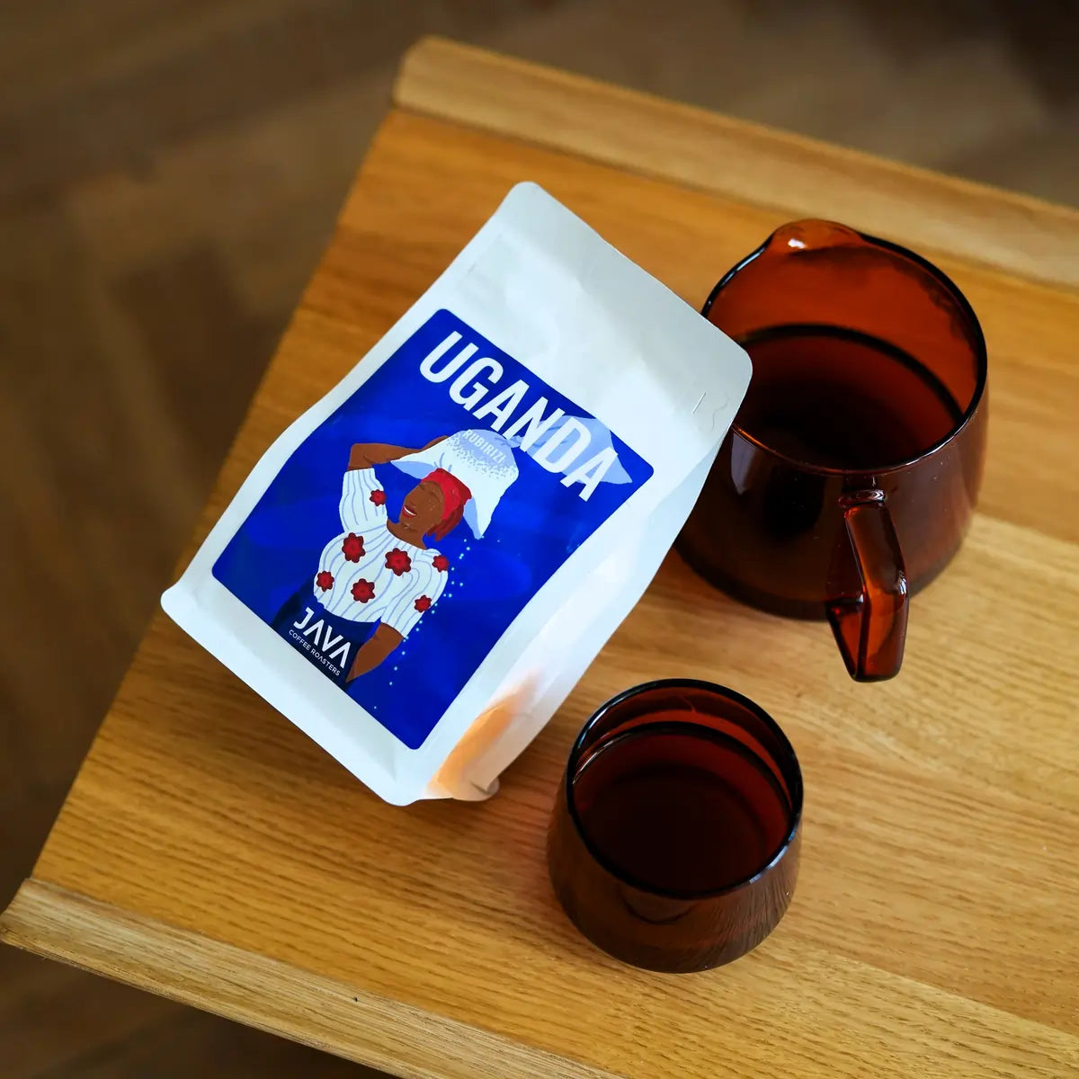 Widok z góry na kawę JAVA Coffee Roasters Uganda Rubirizi 250 g z serwerem i filiżanką na drewnianym stole – świeżo palona kawa specialty 100% Arabica.