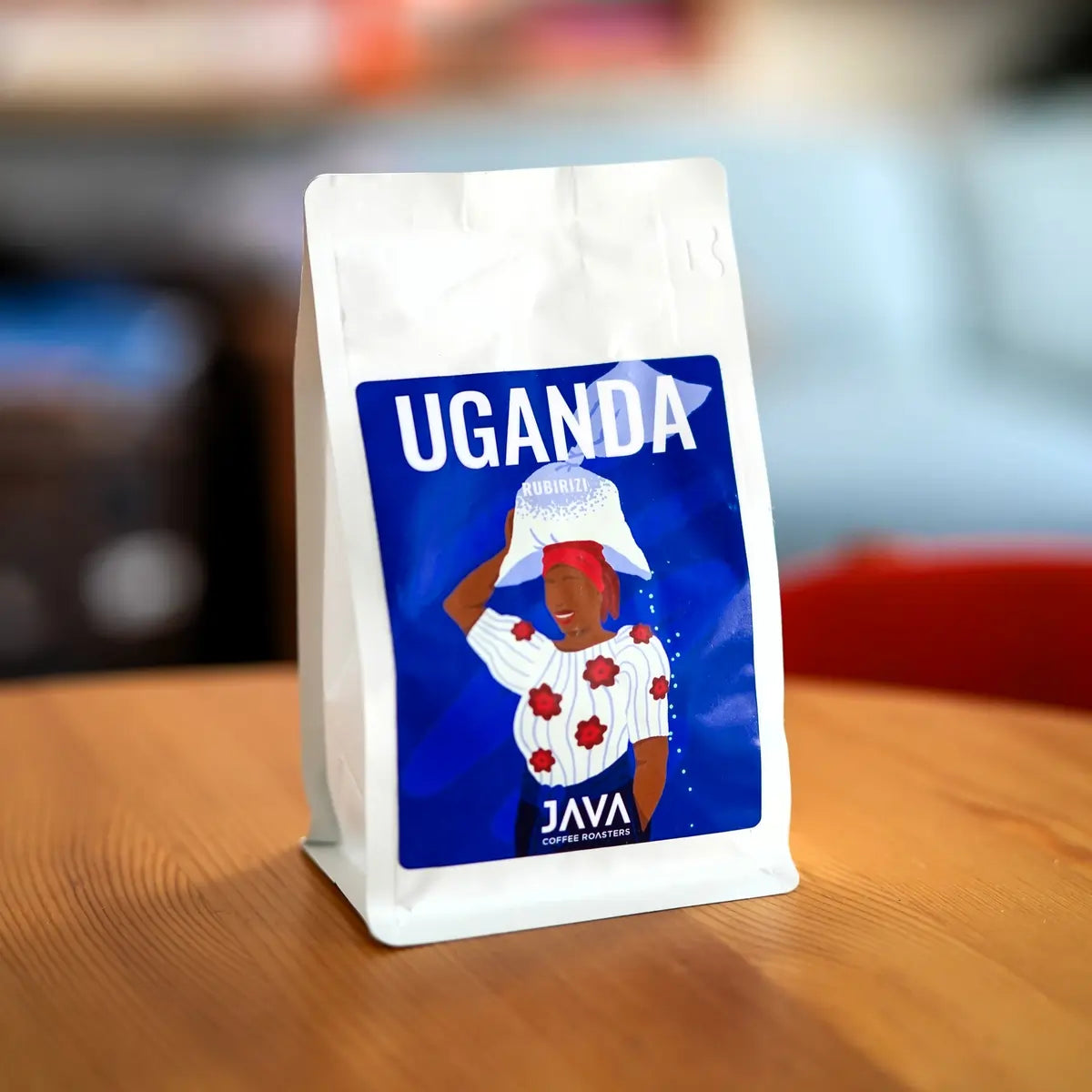 Opakowanie kawy JAVA Coffee Roasters Uganda Rubirizi 250 g ustawione na drewnianym stole w kawiarni – kawa specialty 100% Arabica w ziarnach.