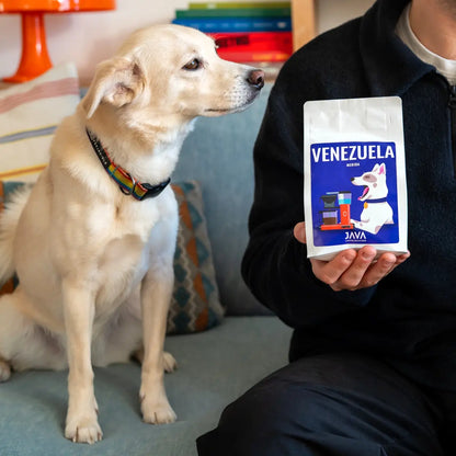 Kawa ziarnista Venezuela Merida 250g JAVA Coffee Roasters obok kubka kawy i psa przy stole w domowym wnętrzu