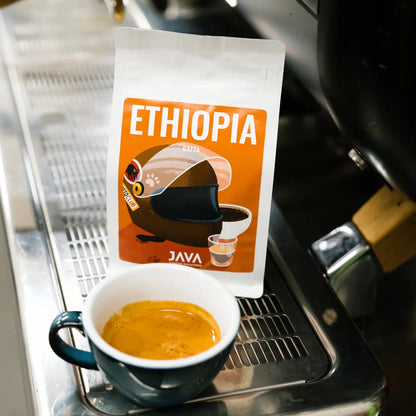 Kawa Ethiopia Gatta od JAVA Coffee Roasters ustawiona przy ekspresie z filiżanką espresso – zdjęcie lifestyle w kawiarni