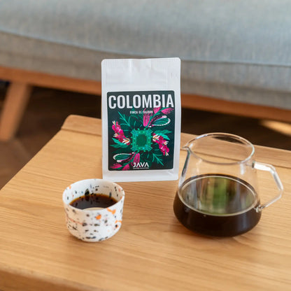 Białe opakowanie kawy specialty Colombia Finca EL Faldon od JAVA Coffee roasters na drewnianym store i dripperem z kawą