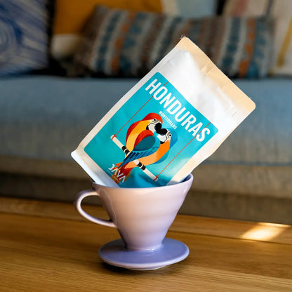 Kawa Java Honduras Montecillos w opakowaniu, ustawiona w ceramicznym dripperze na drewnianym stole, ujęcie lifestyle