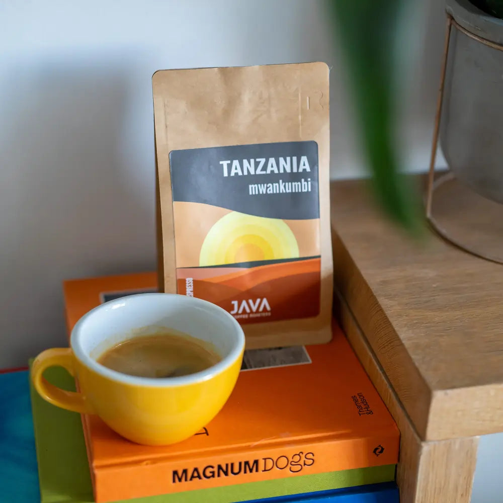 Brązowa torebka kawy Java Coffee Roasters "Tanzania Mwankumbi" z zółtym kubkiem kawy 