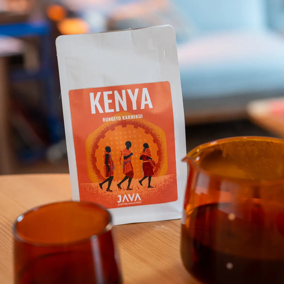 Kawa ziarnista Kenya Rungeto Karimikui JAVA Coffee Roasters w białym opakowaniu na stole, obok dzbanka i szklanki z kawą