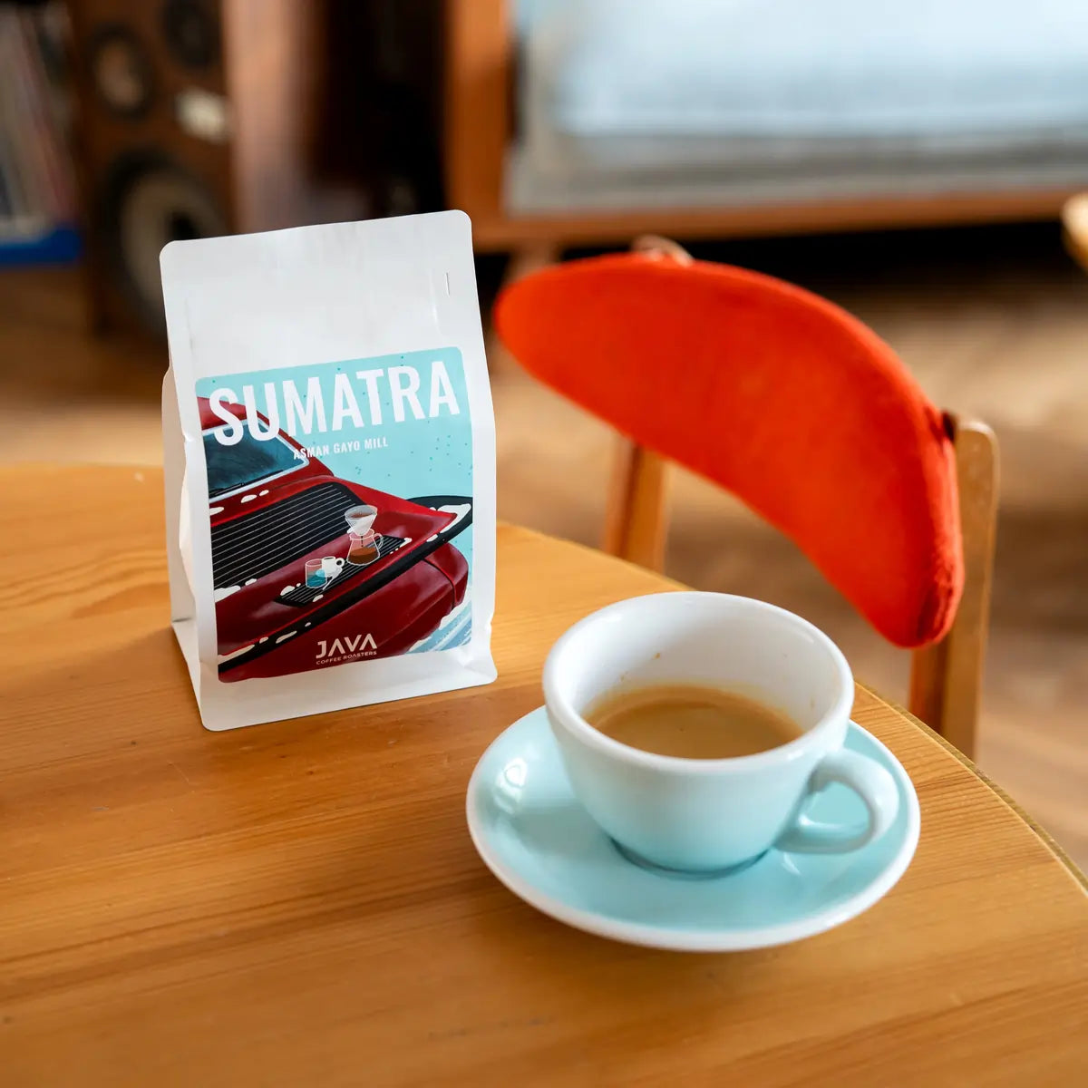 Kawa specialty Sumatra Asman Gayo Mill od JAVA Coffee Roasters – opakowanie kawy obok filiżanki espresso na stoliku w kawiarni, ujęcie lifestyle