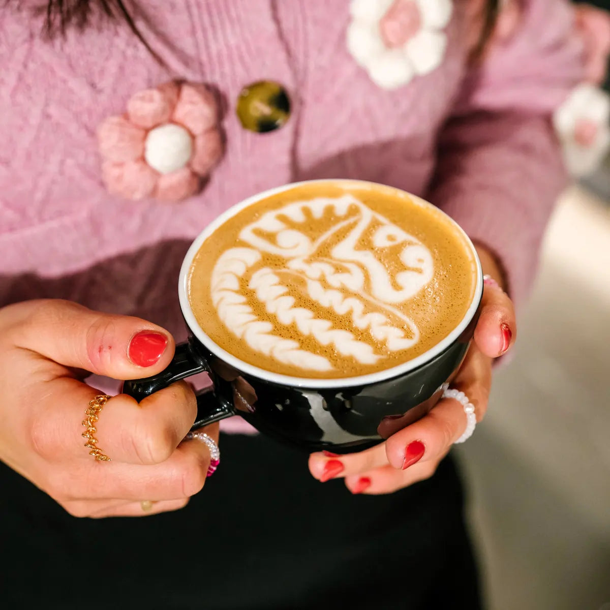 Filiżanka cappuccino z latte artem trzymana w dłoniach, kawa specialty JAVA Coffee – zdjęcie lifestyle