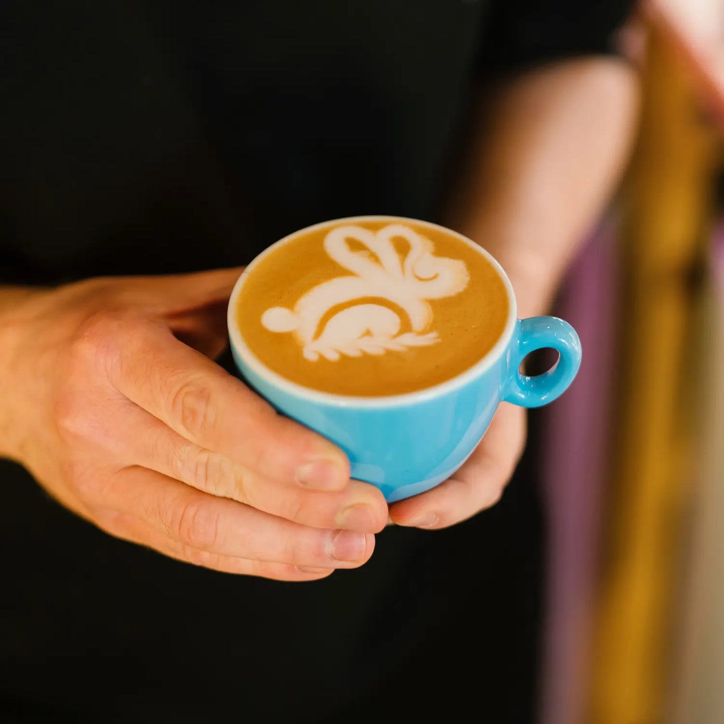 Kawa z latte art w filiżance trzymanej w dłoniach – efekt szkolenia Latte Art w JAVA Coffee