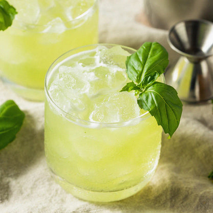 Orzeźwiająca lemoniada bazyliowa z lodem w szklance, ozdobiona świeżą bazylią, idealna na gorące dni, naturalny i orzeźwiający napój