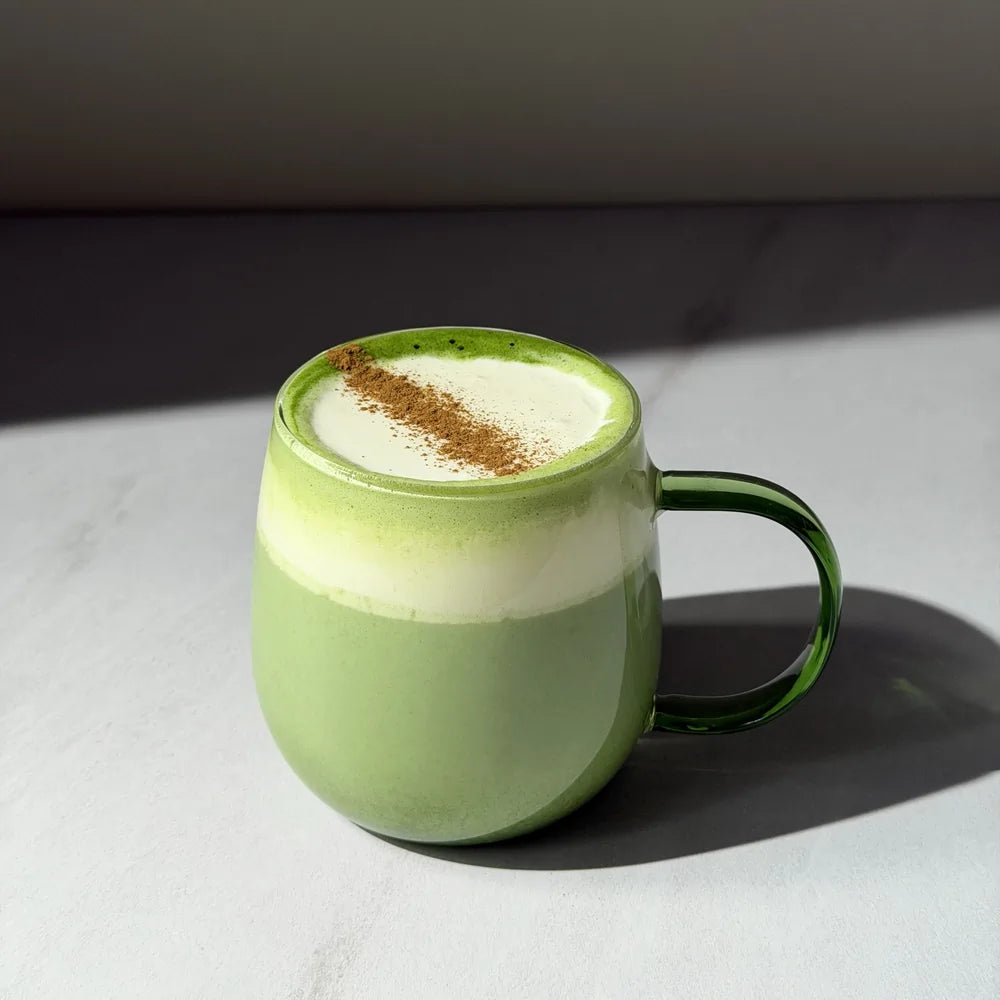 Kremowe matcha latte przygotowane z PerfectTed Ceremonial Grade Matcha i napoju roślinnego Sproud Vanilla, podane w zielonej szklance z pianką mleczną i cynamonem.