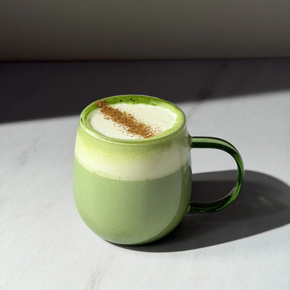 Kremowe matcha latte przygotowane z PerfectTed Ceremonial Grade Matcha i napoju roślinnego Sproud Vanilla, podane w zielonej szklance z pianką mleczną i cynamonem.