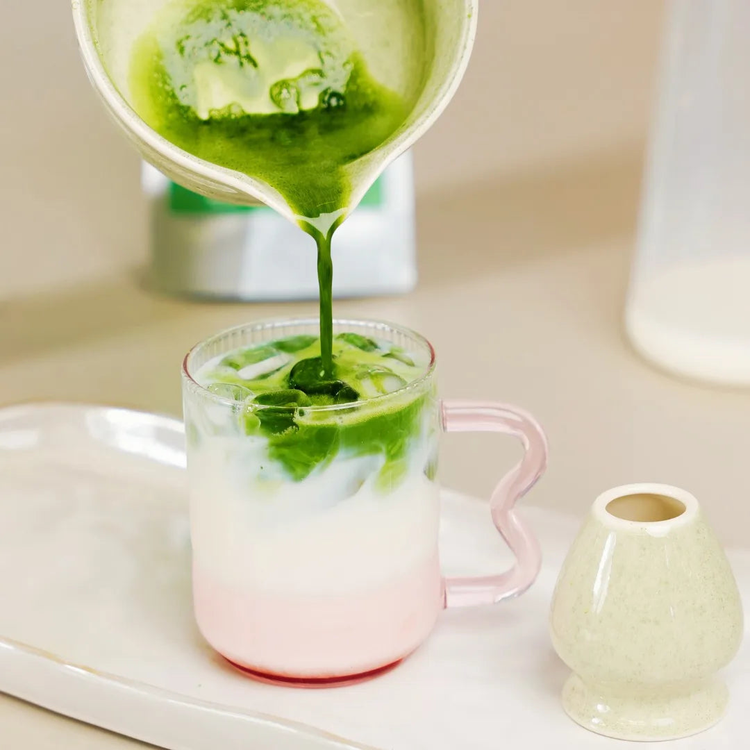 Warstwowe matcha latte na zimno – zielona matcha wlewana do mleka w różowym szkle