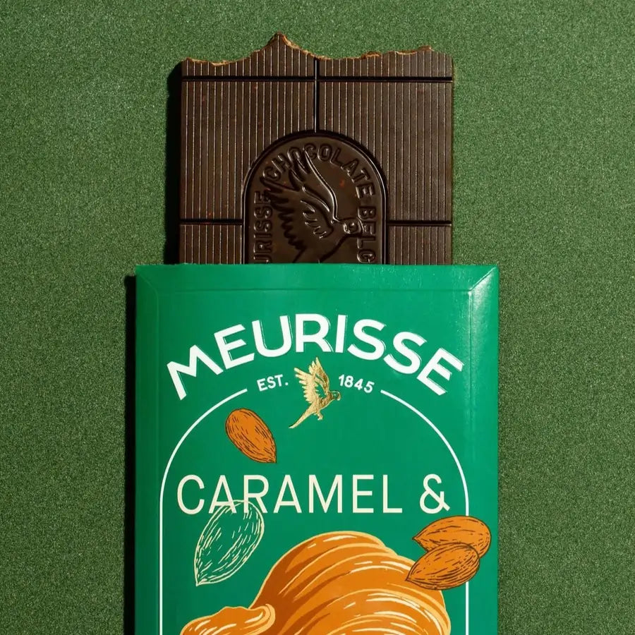 tabliczka czekolady Meurisse Caramel & Almonds częściowo wysunięta z zielonego opakowania na zielonym tle