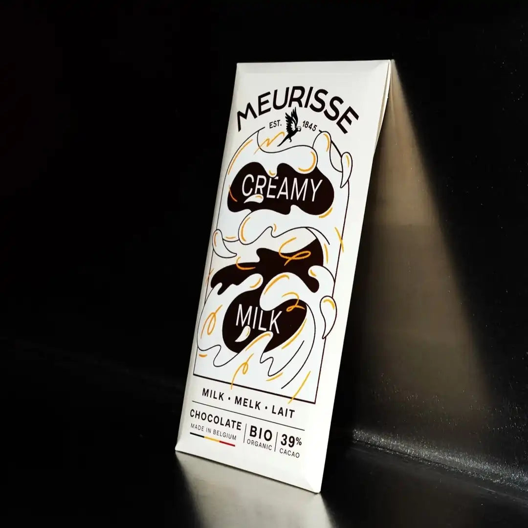 Tabliczka mlecznej czekolady Meurisse Creamy Milk 39% kakao w eleganckim, organicznym opakowaniu sfotografowana na ciemnym tle z delikatnym światłem.