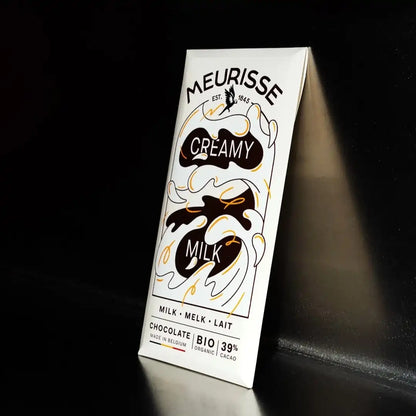Tabliczka mlecznej czekolady Meurisse Creamy Milk 39% kakao w eleganckim, organicznym opakowaniu sfotografowana na ciemnym tle z delikatnym światłem.