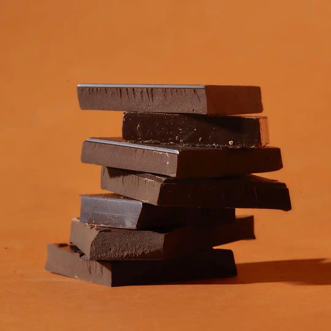 stos kawałków ciemnej czekolady Meurisse na ciepłym, pomarańczowo-brązowym tle