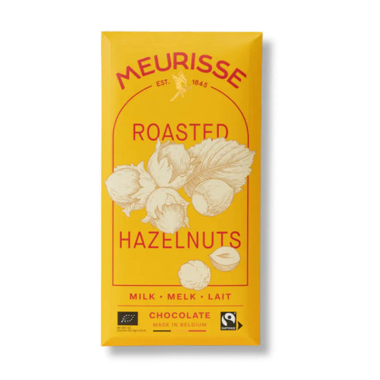 Opakowanie mlecznej czekolady Meurisse Roasted Hazelnuts 39% kakao w żółtym kolorze z ilustracją prażonych orzechów laskowych i oznaczeniami Fairtrade oraz BIO.