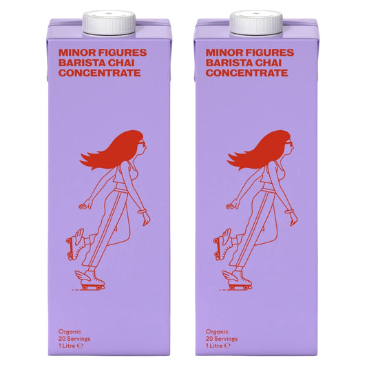 Dwa kartony koncentratu herbaty chai Minor Figures Barista Chai Concentrate 1L w fioletowych opakowaniach z czerwonym nadrukiem postaci na wrotkach.