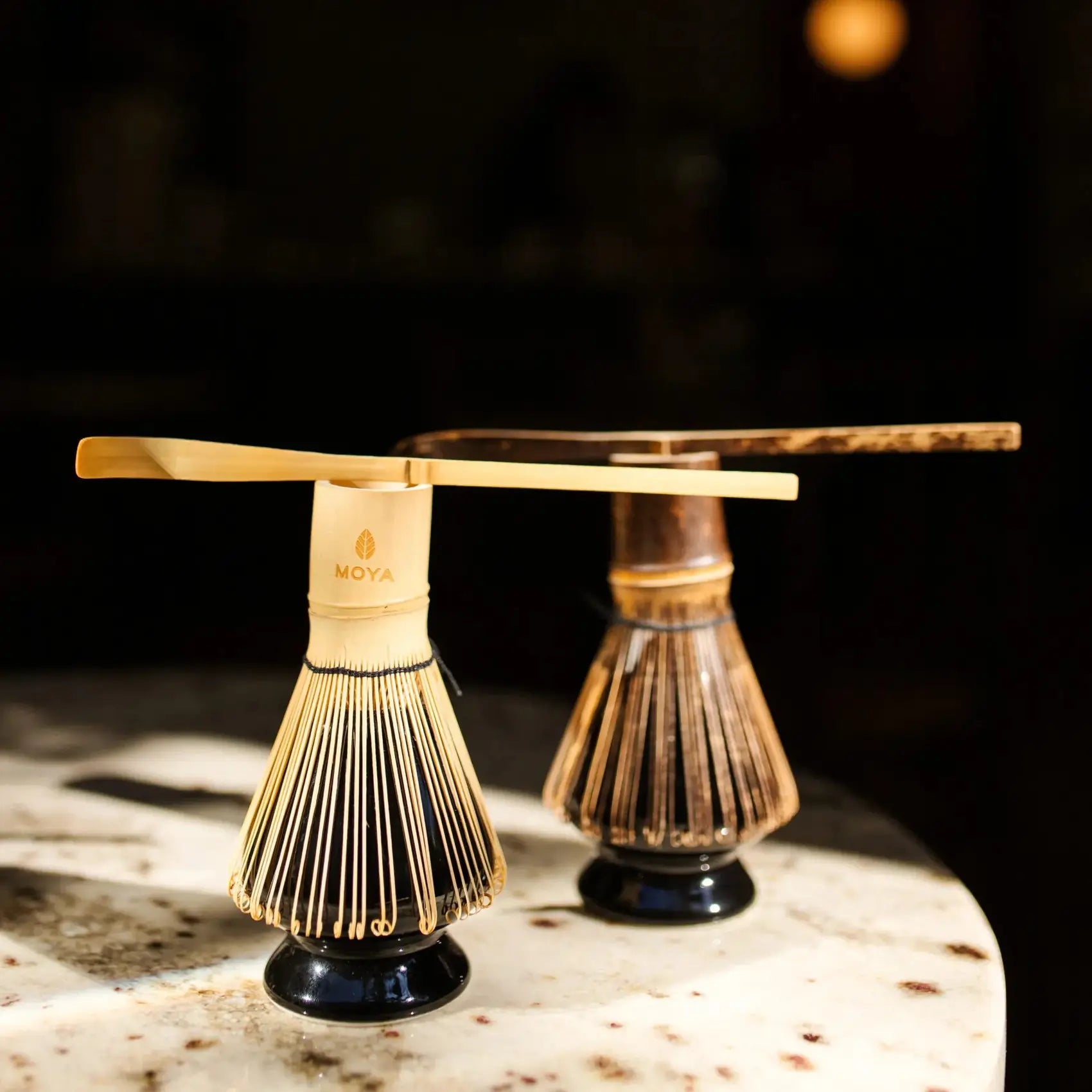 Bambusowa miotełka do matchy MOYA chasen na ceramicznym stojaku kusenaoshi w klimatycznym, ciemnym wnętrzu