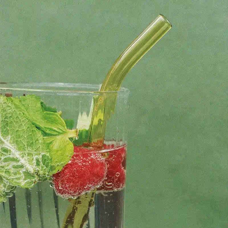 Napój z malinami, listkiem mięty i przezroczystą słomką w szklance na tle zielonej ściany – orzeźwiający, letni drink.