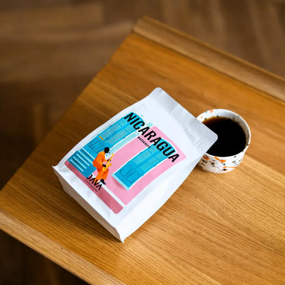 Kawa specialty Nicaragua Matagalpa JAVA Coffee Roasters z filiżanką czarnej kawy na drewnianym stole