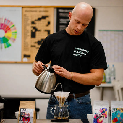 Instruktor przygotowuje kawę metodą V60 podczas szkolenia Home Barista. Praktyczna nauka parzenia kawy przelewowej z wykorzystaniem drippera i czajnika z wylewką typu goose neck.